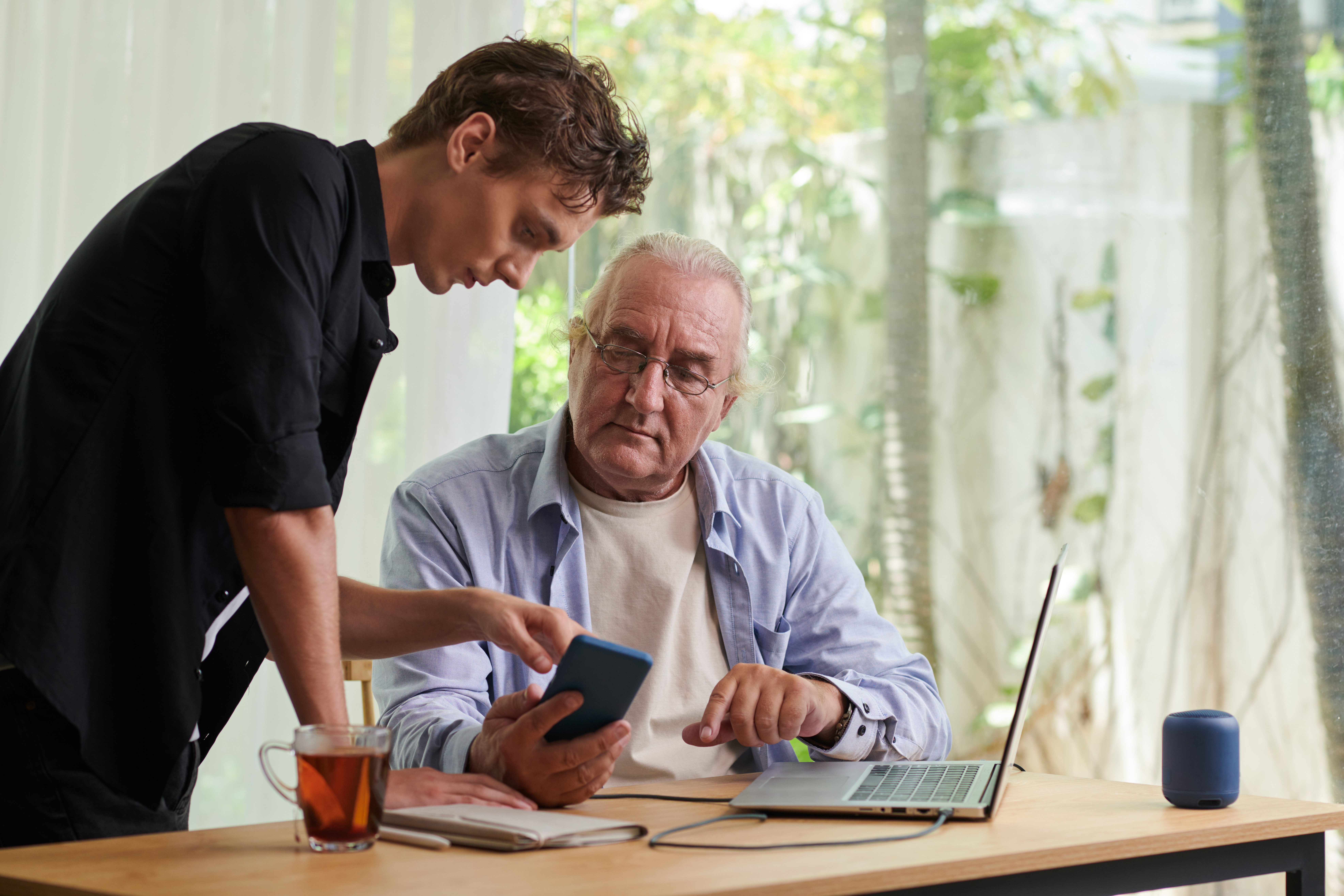 Teenager showing grandfather how to check notifications on smartphone